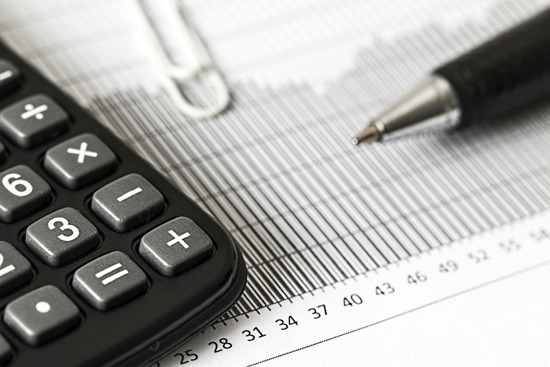 Gros plan d'une calculatrice et d'un stylo sur un graphique à barres, représentant la finance et la comptabilité.