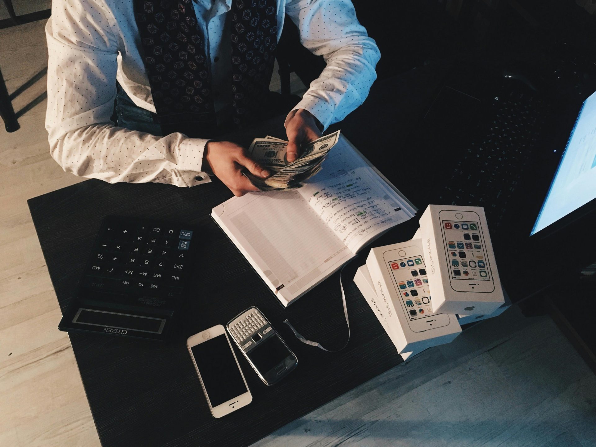 Un homme d'affaires organise ses finances avec des appareils technologiques et de l'argent liquide sur son bureau.