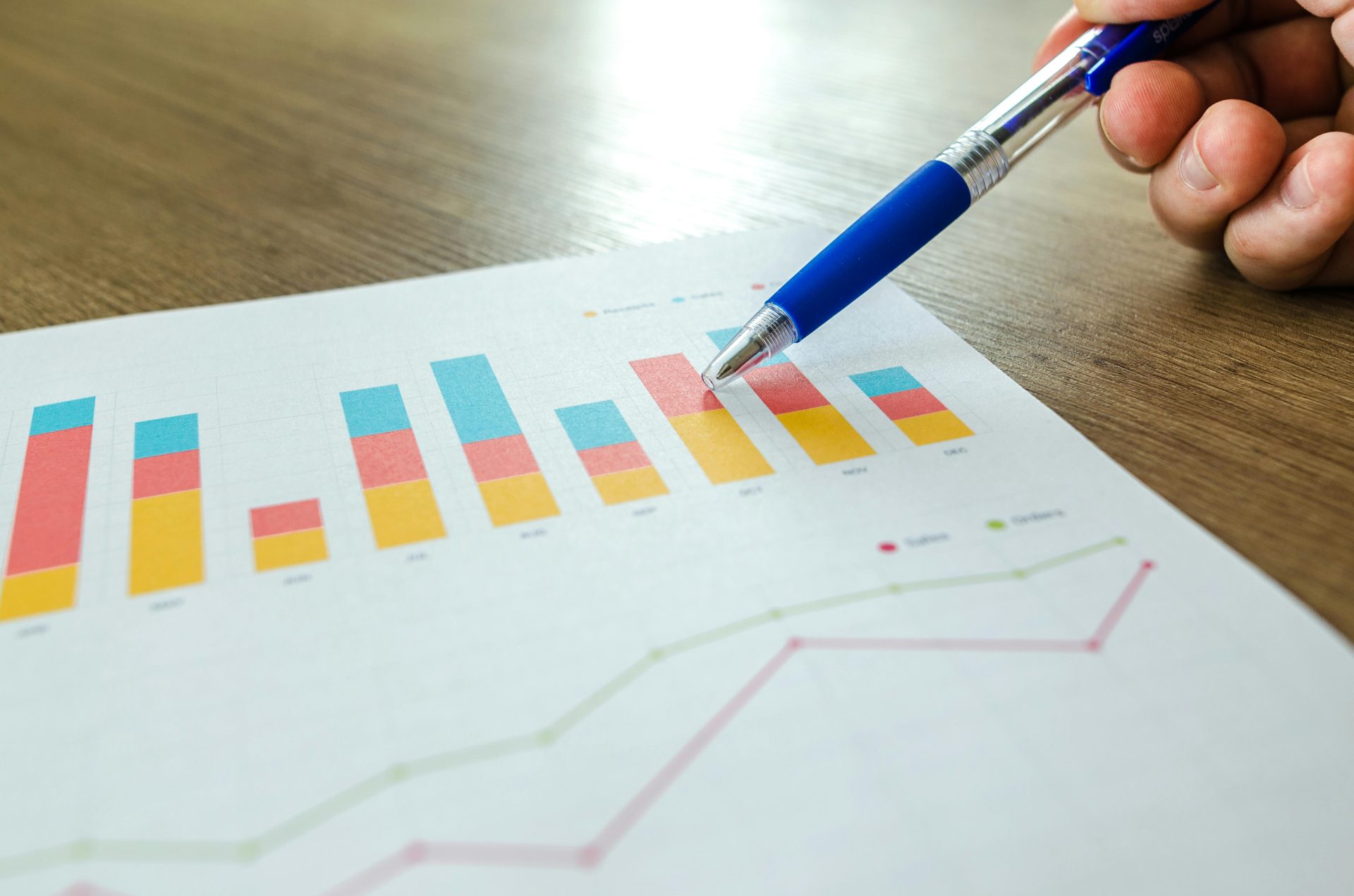 Gros plan détaillé d'une main pointant des cartes colorées avec un stylo bleu sur une surface en bois.