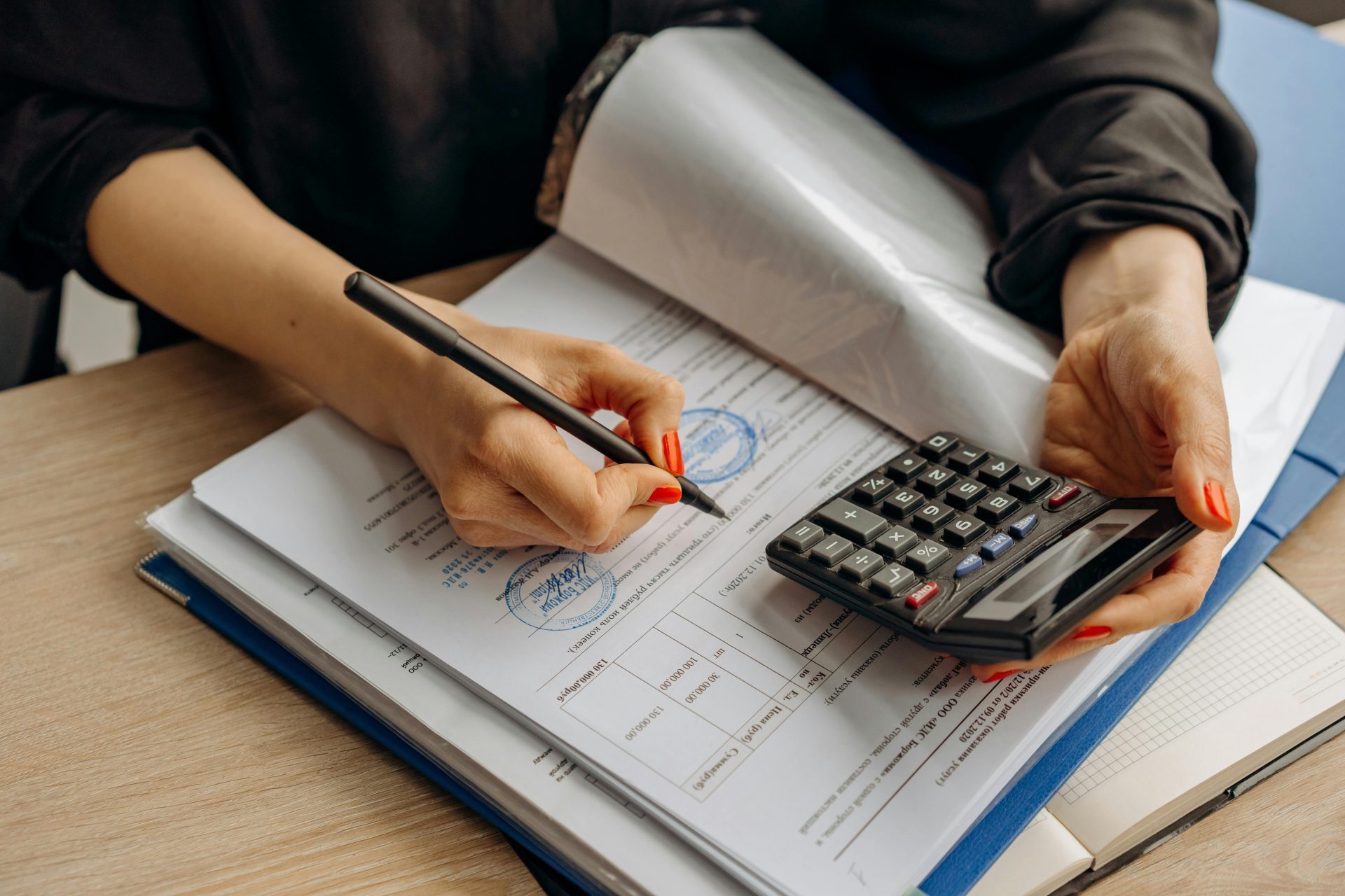 Un comptable utilisant une calculatrice et signant des documents, présentant une analyse financière.