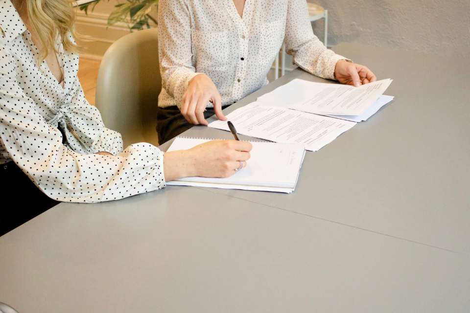 Une main utilisant une calculatrice avec des documents financiers et un cahier, représentant un bureau aménagé pour l'analyse financière.